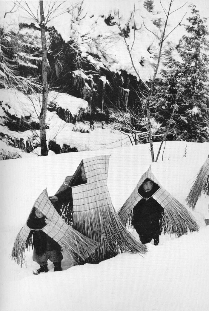 7. Dzieci w tradycyjnych strojach przeciwdeszczowych minobashi, zmierzające na uroczystości noworoczne. Japonia, 1956