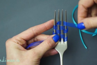 Owija widelec kolorową wstążką i po chwili zaciąga! W prosty sposób stworzyła piękną ozdobę!