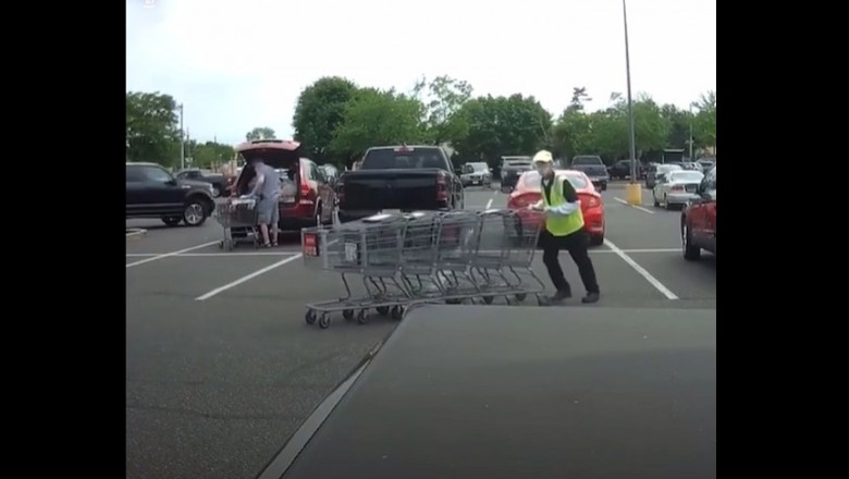 Pracownik marketu z wózkami kontra samochody na parkingu 